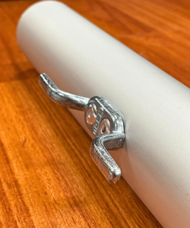 Metal cleat attached to white cylindrical pipe
