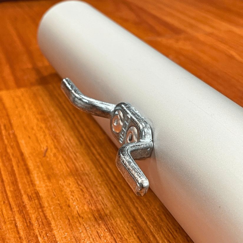 Metal cleat attached to white cylindrical pipe