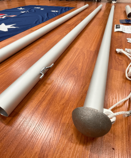 Disassembled flagpole parts on wooden floor