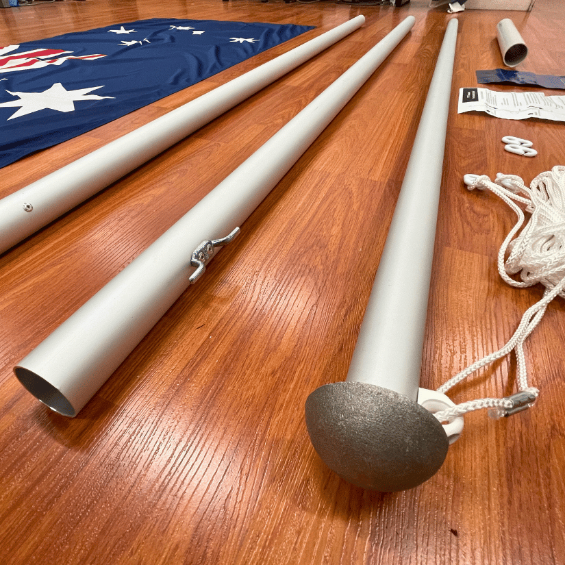 Disassembled flagpole parts on wooden floor