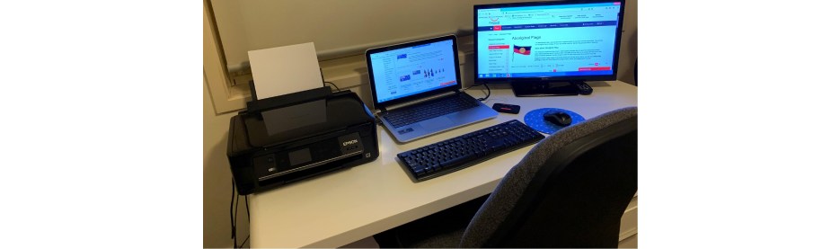 Home office setup with laptop, monitor, and printer