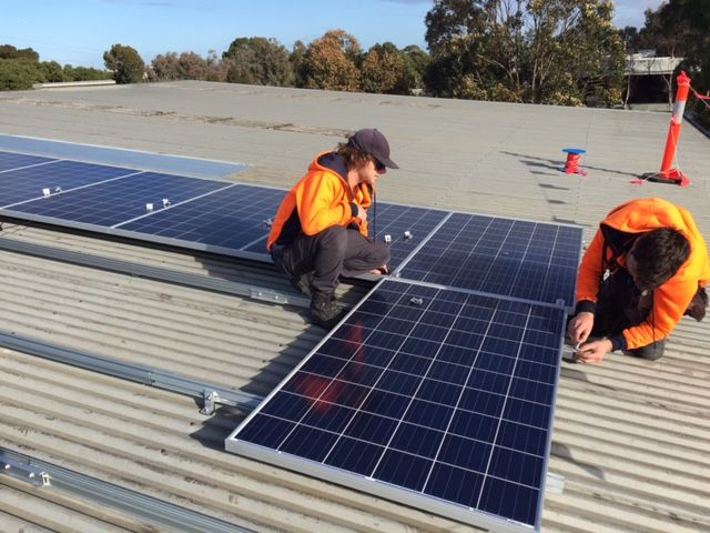 Workers installing solar panels on a rooftop