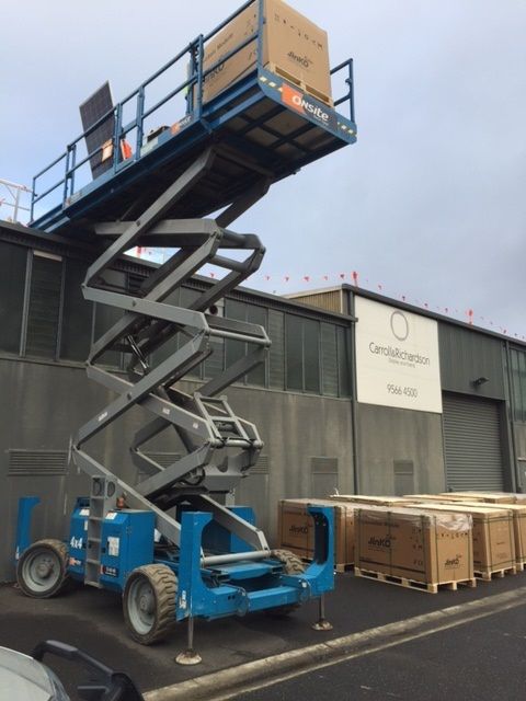 Scissor lift raising boxes near warehouse building