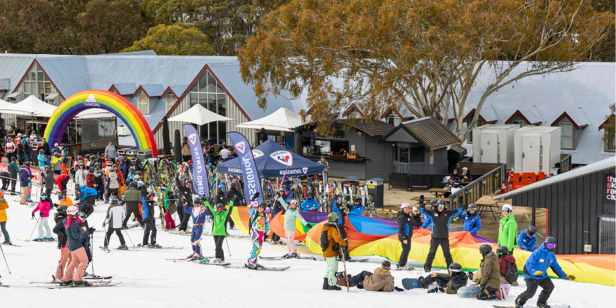 Skiers celebrating under rainbow arch at snowy resort