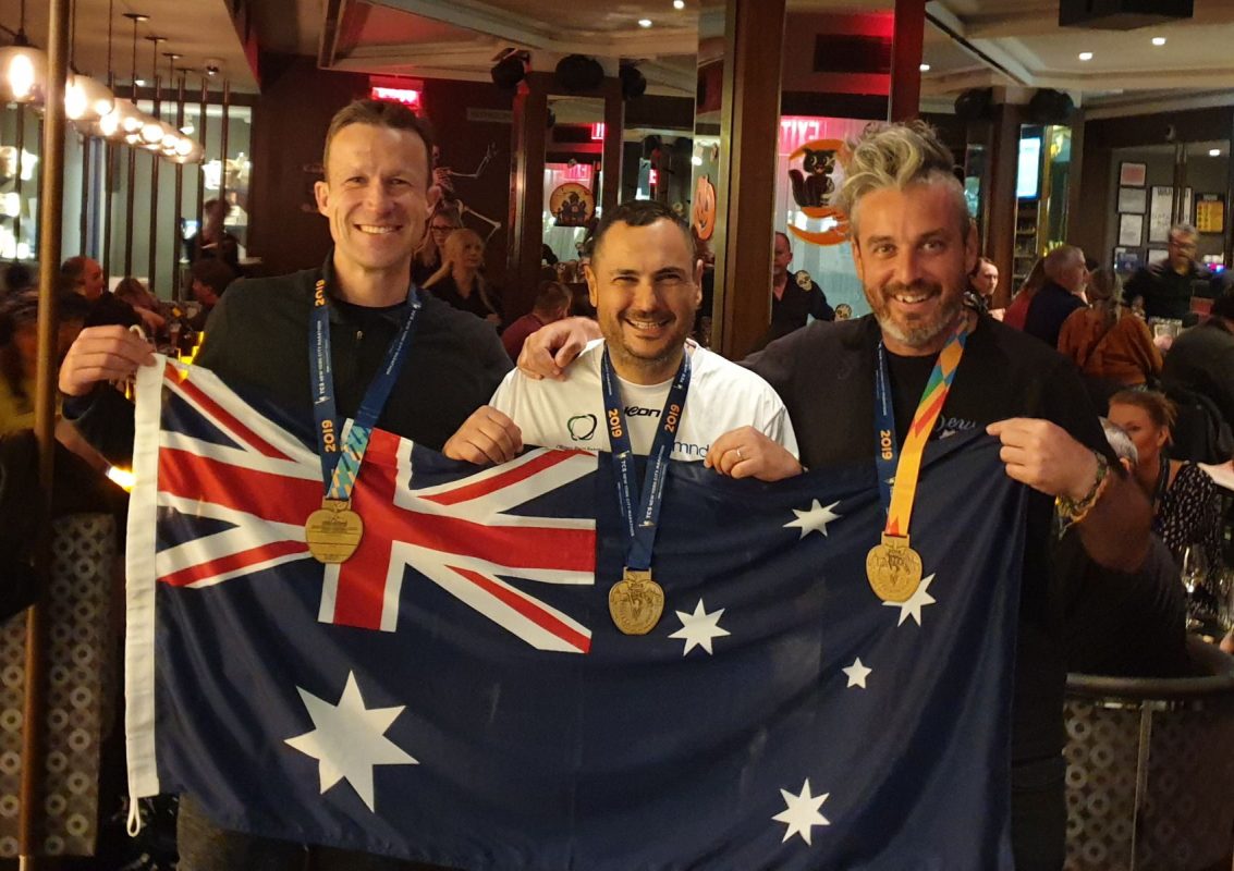 Three medalists holding Australian flag in celebration