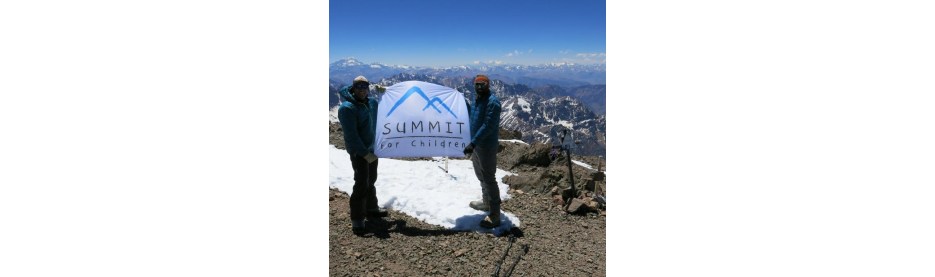 Climbers holding Summit for Children banner on mountain