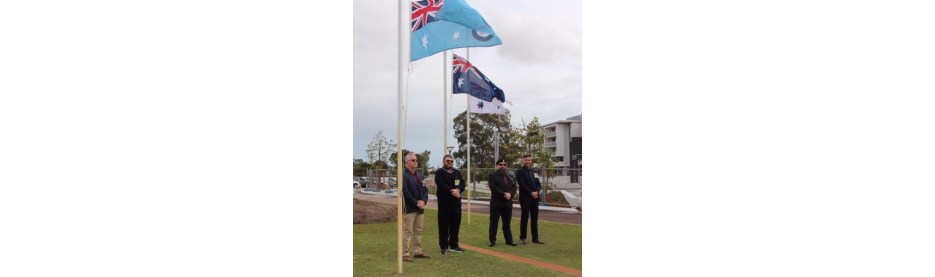 People standing near raised national flags outside