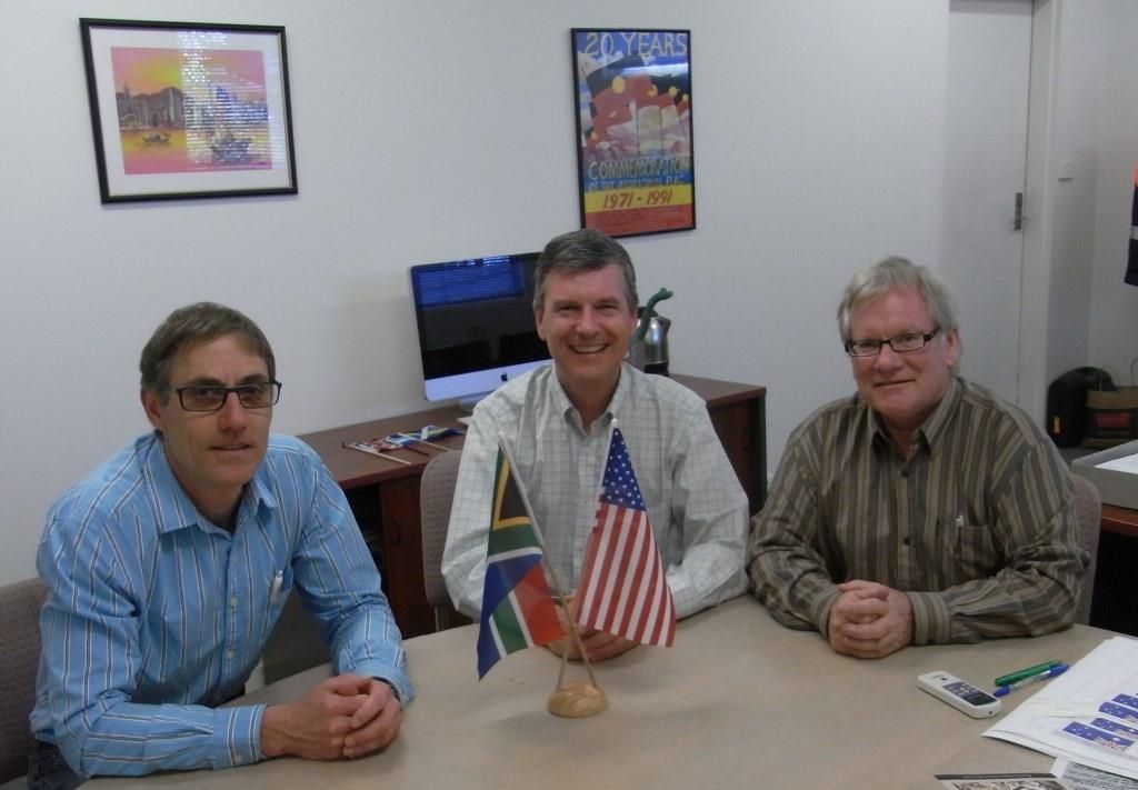 Three men meeting with US and South African flags