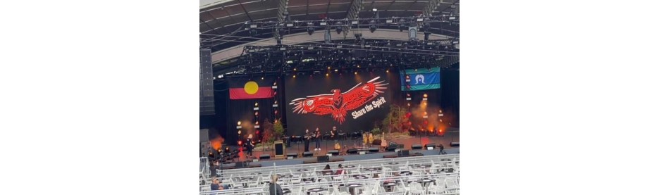 Live band performing on outdoor stage with banners