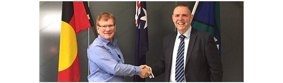 Two men shaking hands near national flags